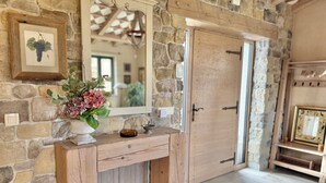 A rustic stone wall with a wooden console table, a mirror, and a door.