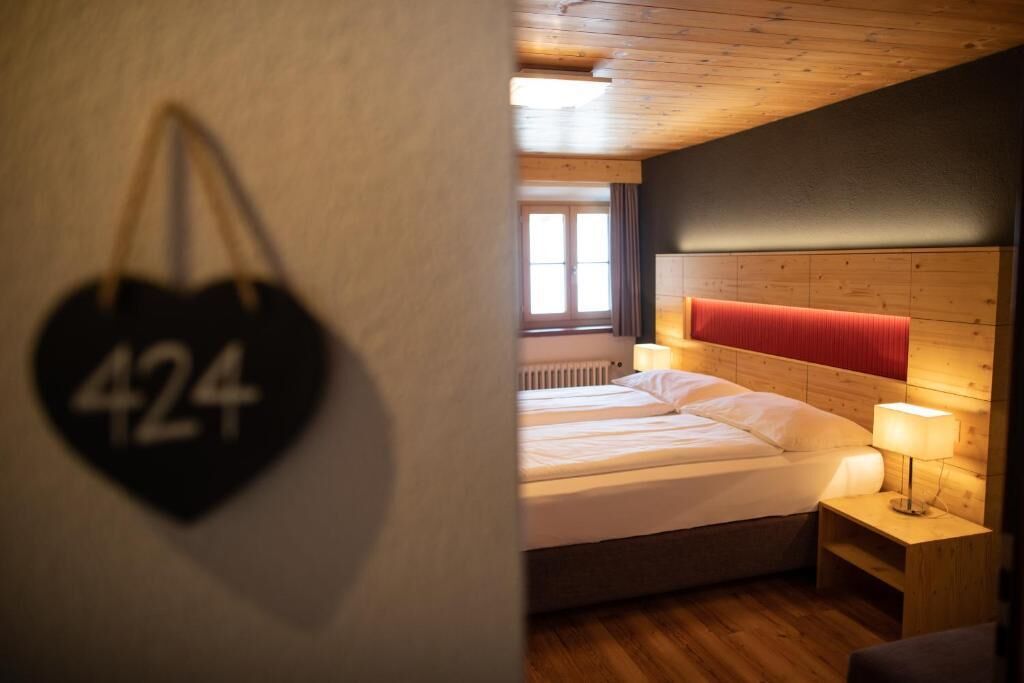 A hotel room with a bed, a nightstand, and a wall-mounted heart-shaped sign with the number 424.