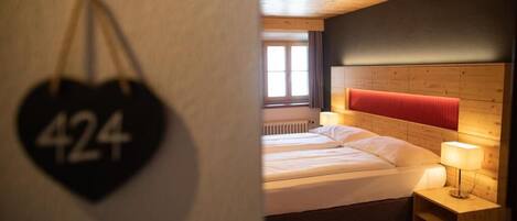 A hotel room with a bed, a nightstand, and a wall-mounted heart-shaped sign with the number 424.