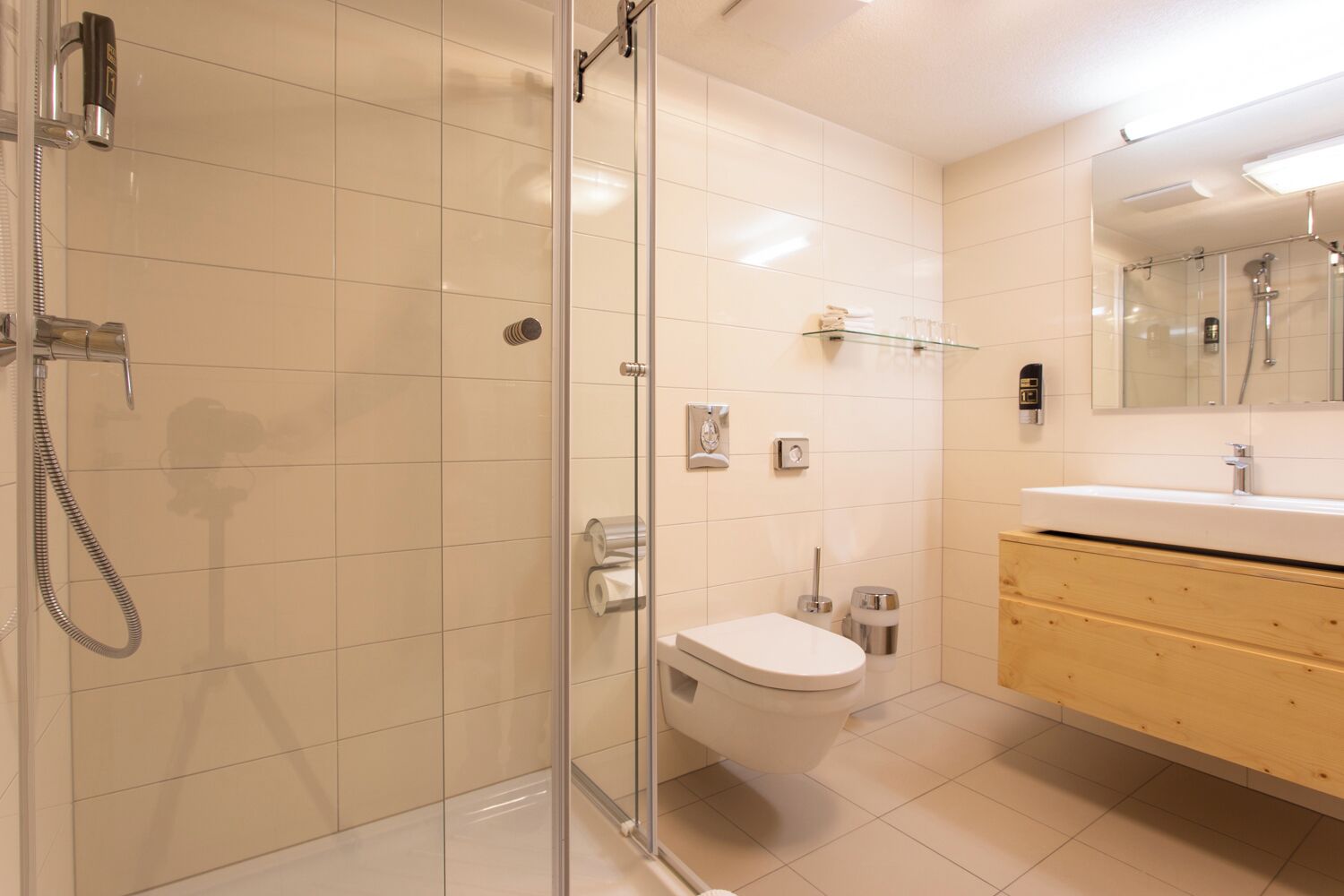 Un baño moderno con ducha de vidrio, inodoro y tocador con espejo.
