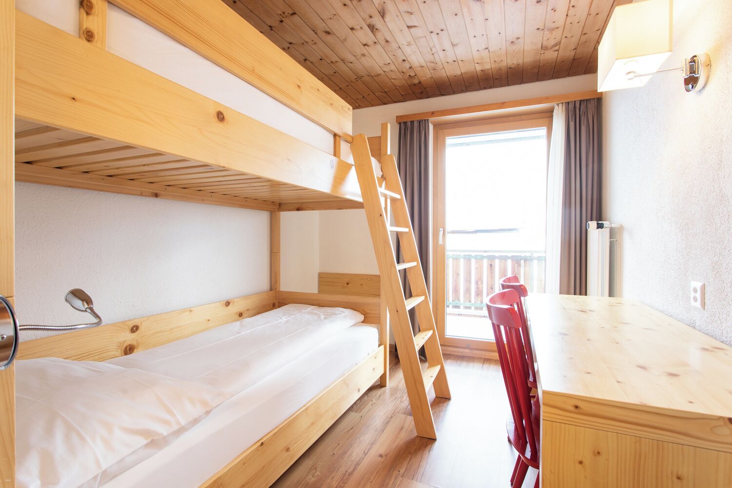 Une chambre avec un lit superposé, une échelle en bois, un bureau et une chaise.