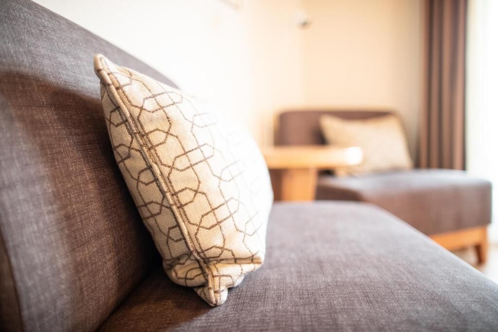 A sofa with a patterned cushion and a small table in the background.