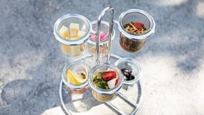 Ett serveringsfat med flera våningar, med olika sorters mat i glasbehållare.