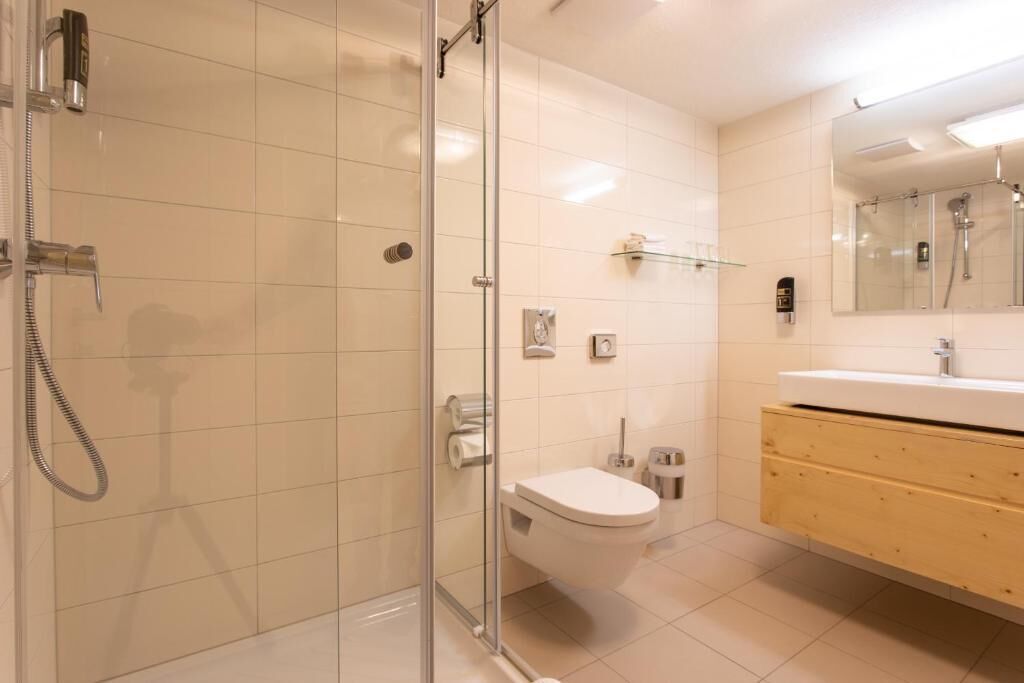 A modern bathroom with a glass-enclosed shower, a toilet, and a vanity with a mirror.