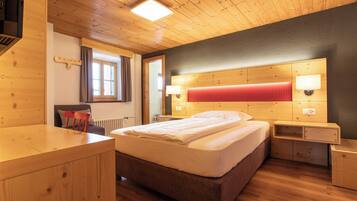 Une chambre avec un plancher en bois, un lit, des tables de chevet et une tête de lit rouge.