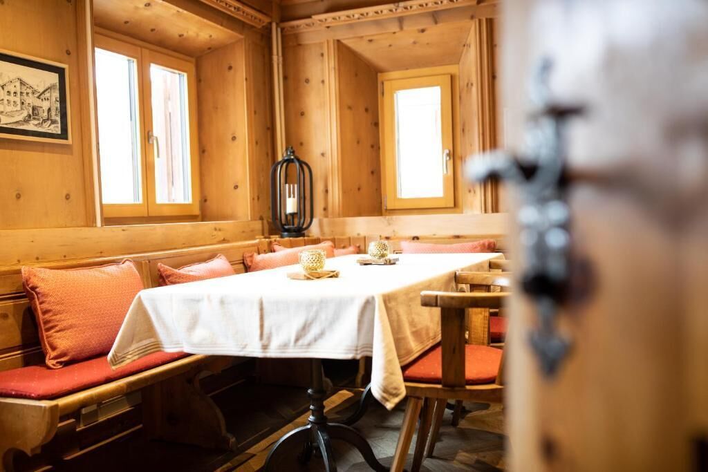 A wooden interior with a long table, benches, and a framed picture on the wall.