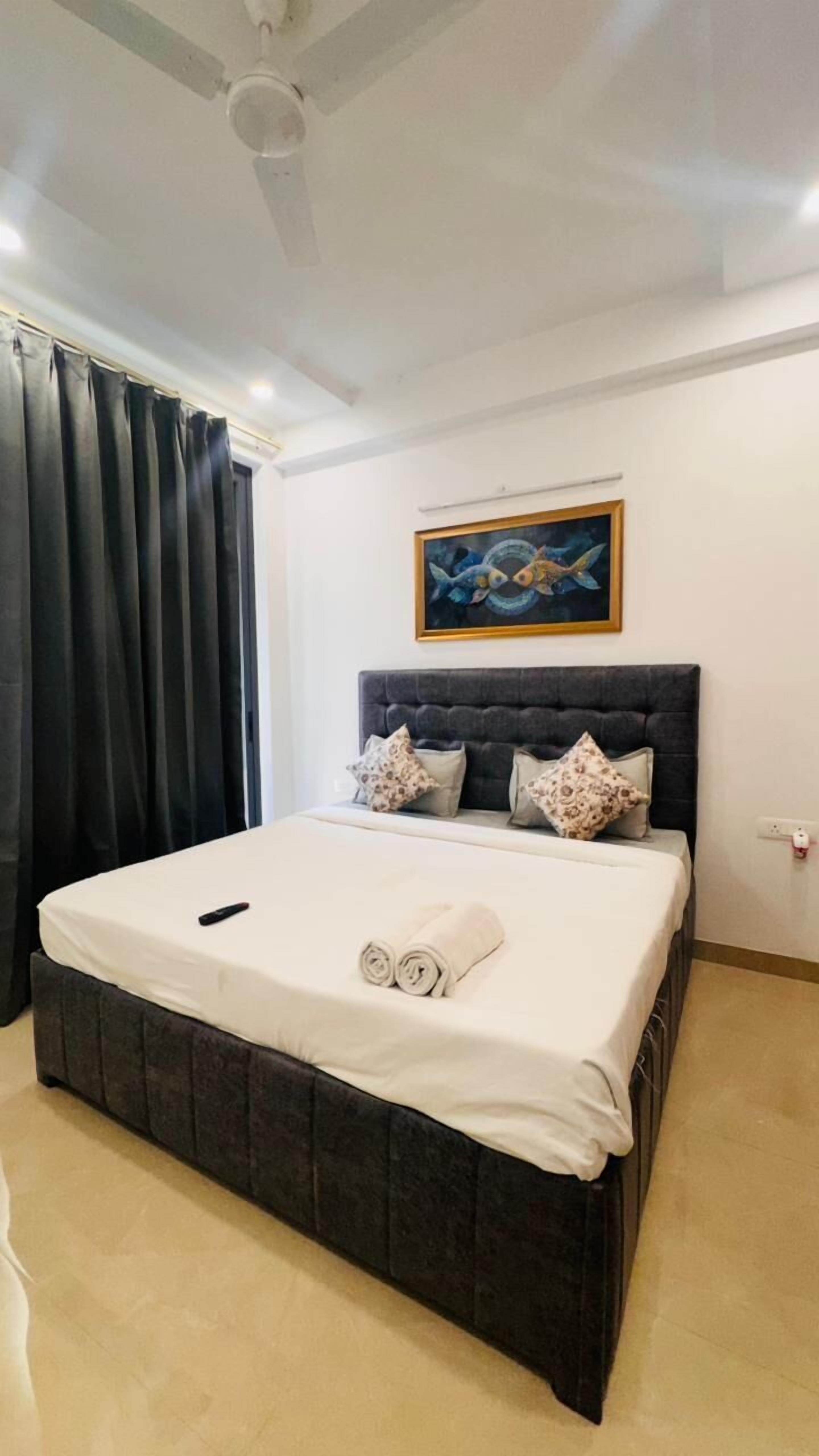 A bedroom with a large bed, dark headboard, and a painting above it.