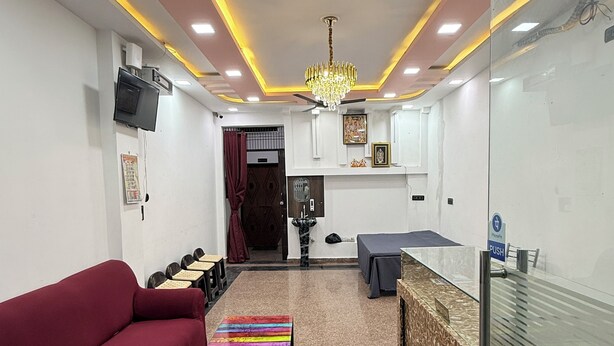 A modern living room with a sofa, a colorful coffee table, a ceiling fan, and a television. - The Vow Cartel Ananta (Varanasi)