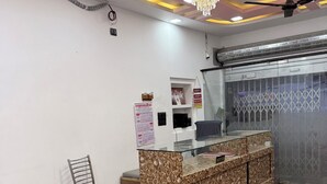 A reception area with a patterned counter, a chair, a calendar, and a ceiling fan. - The Vow Cartel Ananta (Varanasi)