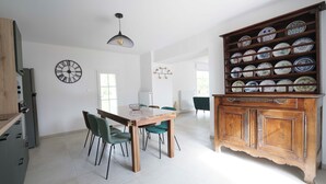 Un comedor con una mesa y sillas de madera, un reloj en la pared y un armario con vajilla.
