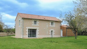 Una casa de dos pisos con techo de tejas, un ventanal grande y una puerta pequeña.