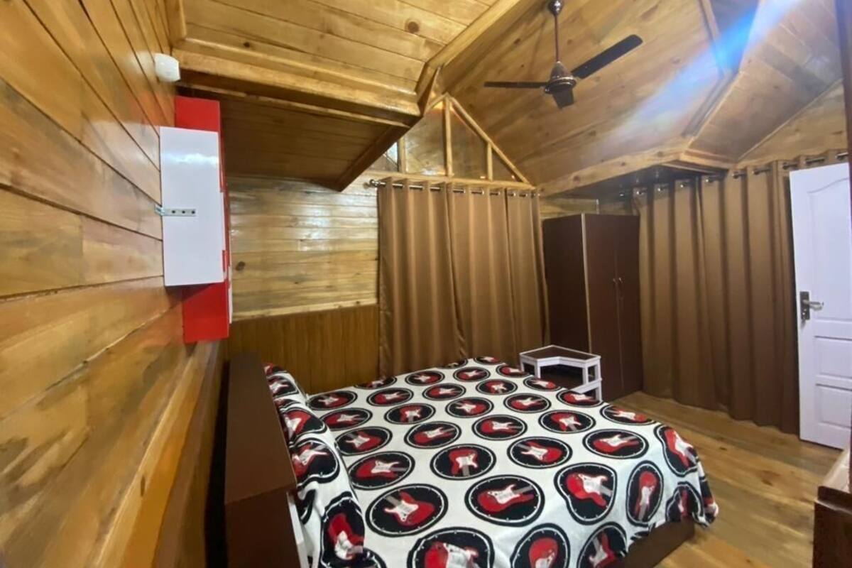 A wooden cabin room with a bed, a ceiling fan, and a door.