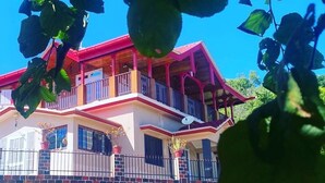 A two-story house with a balcony, a satellite dish, and a brick foundation. - Shanti Kunj Home Stay (Pauri)