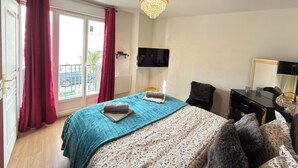 A bedroom with a bed, a dresser, a mirror, and a chandelier. - Royal Rose Apartment With Royal Garden (Le Bourget)