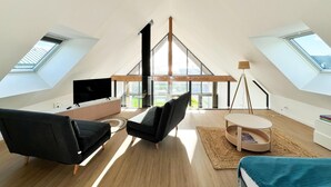 A modern loft bedroom with skylights, a large window, a TV, and a bed. - Architect-designed Villa With sea View (Le Conquet)
