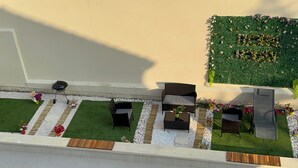 An aerial view of a rooftop garden with seating areas, a small play area, and a green wall with flowers. - Royal Sapphire Apartment With Royal Garden (Le Bourget)