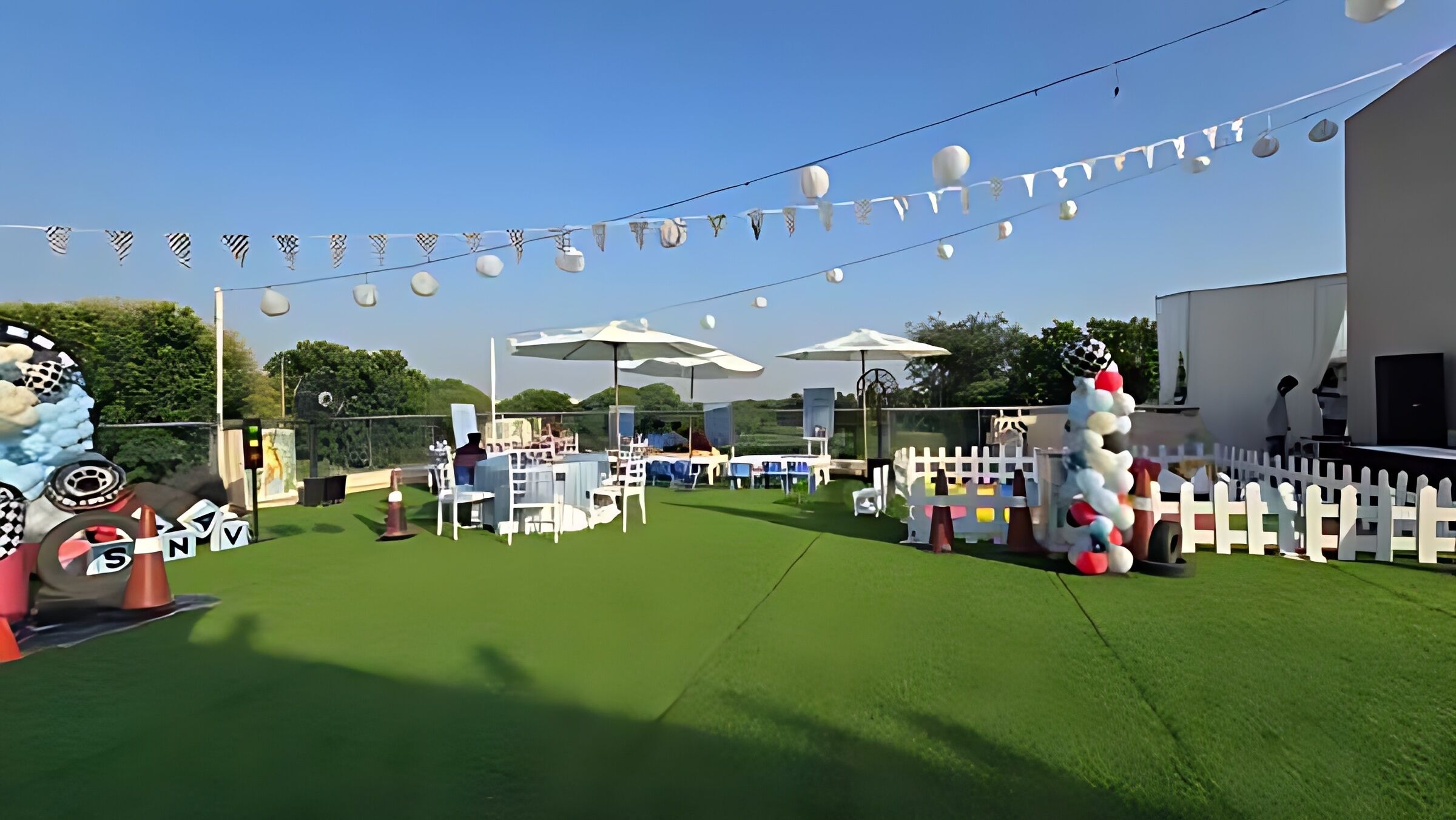An outdoor event space with tables, chairs, and a white picket fence.