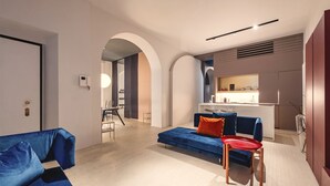 A modern living room with a blue sofa, a red chair, and a kitchen in the background. - ARCHILOFT Brera Gae Aulenti Moscova (Milano)