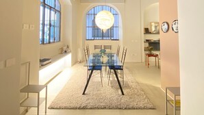 A dining area with a glass table and chairs, a chandelier, and large windows. - ARCHILOFT Brera Gae Aulenti Moscova (Milano)