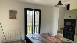 A kitchen with a Bosch oven, a dining table with placemats, a wooden chair, and a view through a sliding door to a balcony.