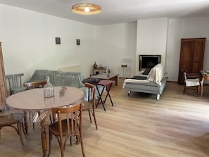 Una sala de estar con una mesa redonda de madera, un sofá gris, un mueble de madera y un televisor.
