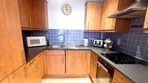 Cocina compacta con armarios de madera, microondas, fregadero y estufa.