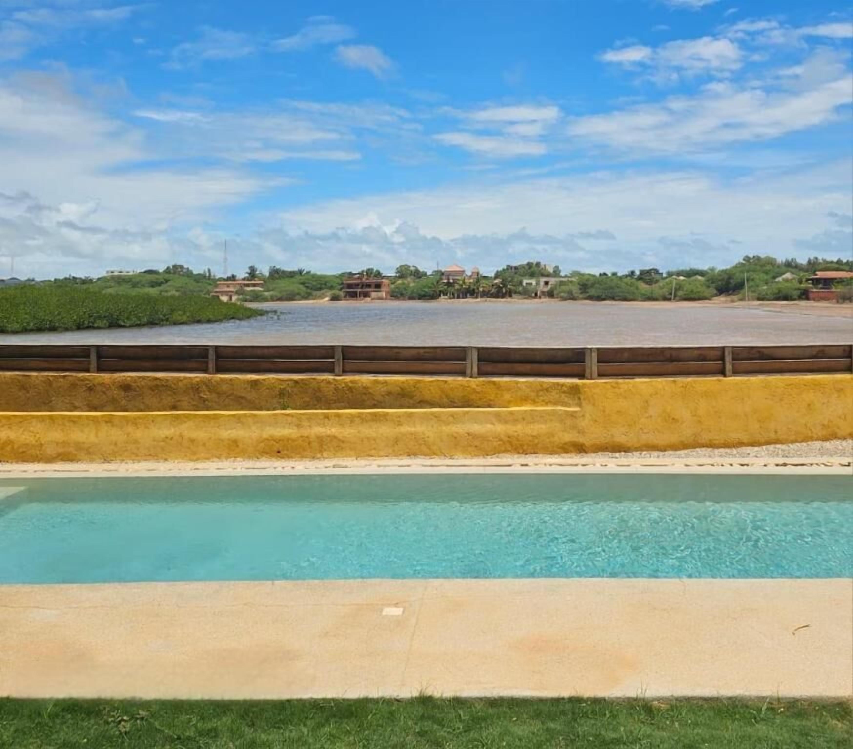 A swimming pool with a clear view of the surrounding landscape, including a distant building and greenery.