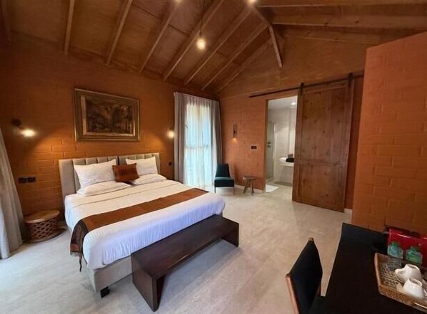 A bedroom with a large bed, a bench, a chair, and a small table. There is a door leading to another room. - Aerys Village (La Somone)