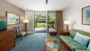 Ein Hotelzimmer mit Fernseher, einer Couch, einem Essbereich mit Stühlen, einem gemusterten Boden und Blick ins Freie.