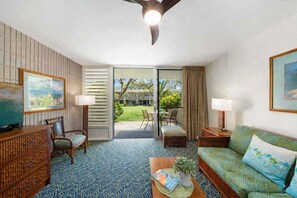 A hotel room with a TV, a sofa, a dining area with chairs, a patterned floor, and a view of the outdoors. - New Listing!  1BR garden-view Hawaiian style furnishings short walk to beach- Napili Shores F149 (Lahaina)