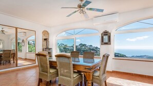 Un comedor con mesa y sillas, ventanas amplias y vistas al paisaje.