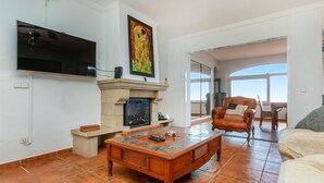 Una sala de estar con chimenea, televisor y un amplio ventanal.