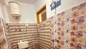 Kylpyhuone, jossa on wc, suihku ja punainen ämpäri.