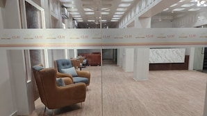 A hotel lobby with a wooden floor, a reception desk, and a seating area with brown leather chairs. - Hotel Camel managed by CLAY (Mundra)