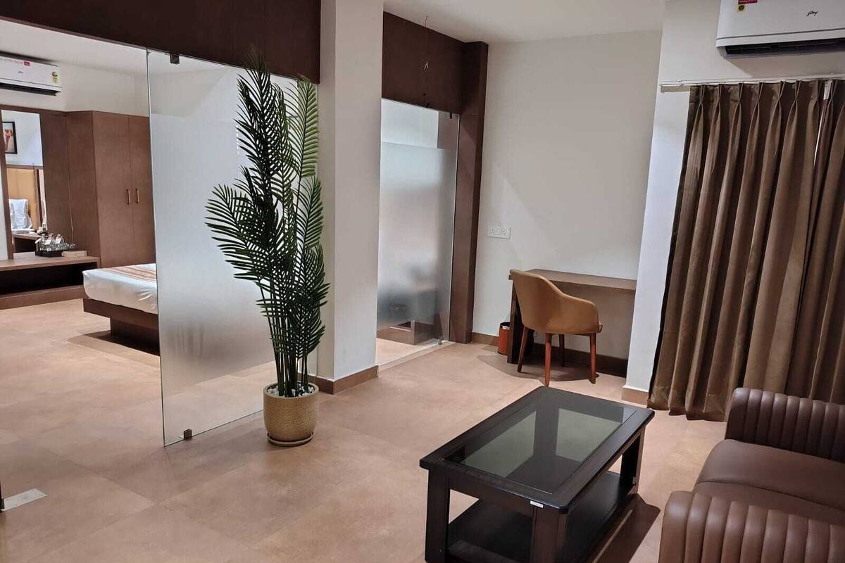 Ein modernes Wohnzimmer mit einem Glastisch, einer Couch, einem Schreibtisch und einer Topfpflanze.