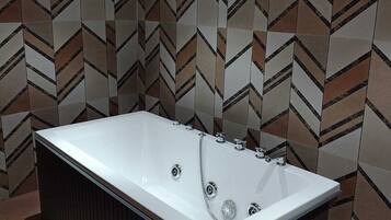 A modern bathroom with a freestanding bathtub, a shower area, and a patterned wall.