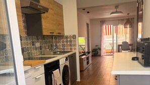 Een moderne keuken met een wasmachine, een fornuis en een eethoek met een tafel en stoelen.