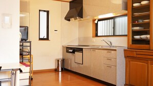 A compact kitchen with a dishwasher, a sink, and wooden cabinets. - Eco inn - Hostel (Inazawa)