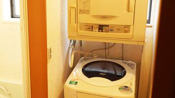A compact, single-room layout with a washing machine and a small cabinet above it.