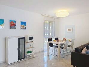 A modern living room with a dining area, a white refrigerator, a TV on a stand, and artwork on the walls. - Lovely apartment for 4 people with WIFI, TV, balcony and panoramic view (Locarno)