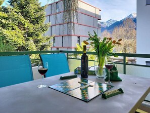 A table with a Scrabble board, a bottle of wine, and a vase of flowers on a balcony with a mountain view. - Lovely apartment for 4 people with WIFI, TV, balcony and panoramic view (Locarno)
