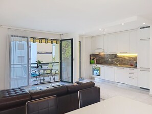 A modern kitchen with white cabinets and a marble backsplash, a dining area with a black leather sofa, and a sliding glass door leading to an outdoor patio. - Beautiful apartment for 4 guests with WIFI, TV, balcony and panoramic view (Locarno)