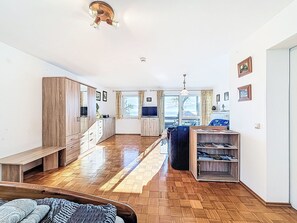 Eine geräumige Küche mit Holzausstattung, eine Essecke mit einer Bank und ein Blick ins Freie durch große Fenster.