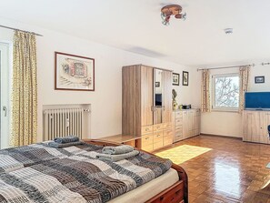 Ein Schlafzimmer mit Bett, Kleiderschrank, Heizkörper und einem Fenster mit Vorhängen.