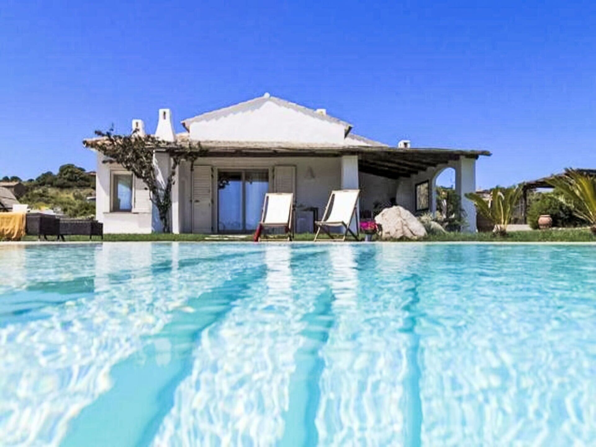 Una casa con piscina, patio cubierto y fachada blanca.