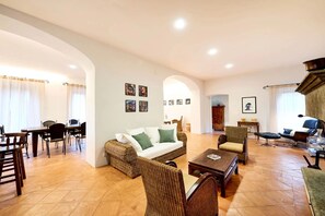 Ein großzügiger Wohnbereich mit Sofa, Sesseln, Esstisch und Couchtisch.