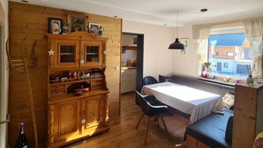 A cozy room with a wooden cabinet, a dining table with chairs, and a window with a view of buildings outside. - "Chalet Imberg", Oberstaufen-Steibis (Oberstaufen)