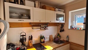 A compact kitchen with white cabinets, a built-in oven, a coffee machine, and a window with a view of the outside. - "Chalet Imberg", Oberstaufen-Steibis (Oberstaufen)