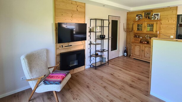A living room with a TV, a fireplace, a wooden cabinet, and a chair. - "Chalet Imberg", Oberstaufen-Steibis (Oberstaufen)