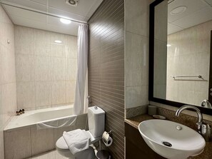 A modern bathroom with a bathtub, toilet, and sink. - Silkhaus Premium 1bdr in Dubai Production City (Dubai)